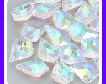 May include: A collection of clear, faceted acrylic beads with an iridescent finish. Each bead features a teardrop or irregular geometric shape with multiple angled surfaces that reflect light, creating a shimmering rainbow effect across the surface.