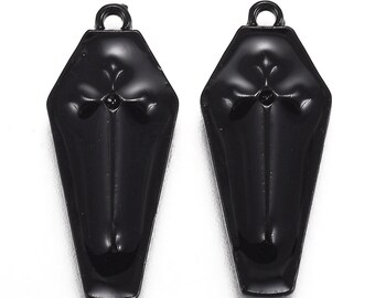 May include: Two black coffin-shaped charms with a cross design. These charms are perfect for adding a gothic touch to jewelry projects.