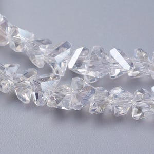 May include: A strand of clear crystal beads with a faceted, triangular shape. The beads are strung together to create a delicate and sparkling necklace or bracelet.