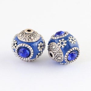 May include: Two blue and silver round beads with intricate designs and blue rhinestones.