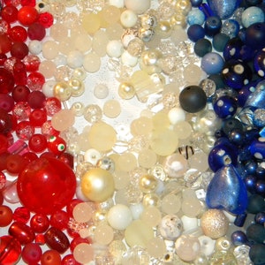Peut inclure: Une collection de perles rouges, blanches et bleues. Les perles sont de formes et de tailles vari&eacute;es, notamment rondes, carr&eacute;es et en forme de c&oelig;ur. Certaines perles sont transparentes, tandis que d'autres sont opaques.