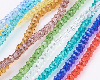 May include: Assortment of faceted glass beads in various colors, including clear, light blue, turquoise, green, brown, purple, and red. The beads are strung together in rows, showcasing their sparkle and shine.