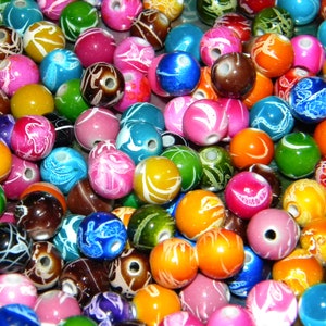 May include: A collection of colorful round beads with various patterns and designs. The beads are made of plastic and have a glossy finish.