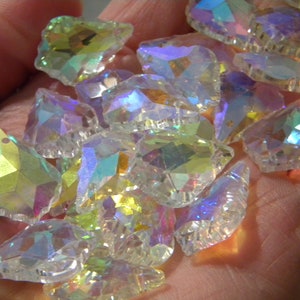 May include: A collection of iridescent glass teardrop-shaped beads with a variety of colors, including clear, green, and purple.