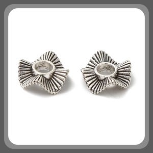 May include: Two silver metal bead spacers with a wavy, ruffled design. The spacers have a round hole in the center.