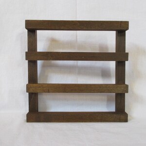 May include: A dark brown wooden shelf unit with three shelves. The shelf unit is made of unfinished wood and has a rustic look.