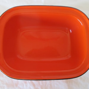 May include: Orange ceramic baking dish with a black rim. The dish is empty and ready to be used.
