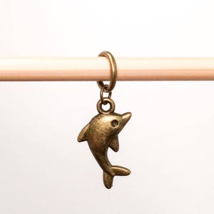 May include: A bronze dolphin charm with a ring for attaching to a knitting needle or crochet hook.