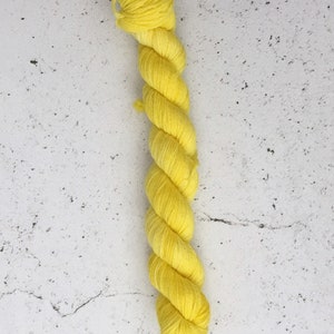 May include: A skein of bright yellow yarn, tightly twisted and ready for crafting. The yarn is a vibrant, sunny yellow color, perfect for knitting or crocheting projects. The texture appears soft and inviting.