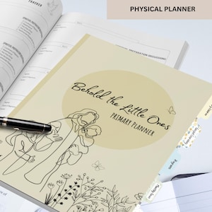 May include: A beige planner titled Behold the Little Ones Primary Planner with a line art illustration of a figure holding a child, surrounded by flowers and butterflies. The planner features tabbed dividers and rests on an open book with text.