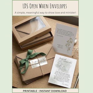 May include: A set of brown kraft paper envelopes in a box with a clear window, tied with a green ribbon and twine. Two white cards are included, one featuring a floral illustration and text, and another with a line drawing and printed text.