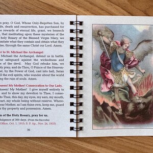 May include: Open booklet with spiral binding, featuring text and an illustration of Saint Michael the Archangel. The illustration depicts a figure with wings, holding a sword, and standing over a figure. The text includes prayers and religious information.