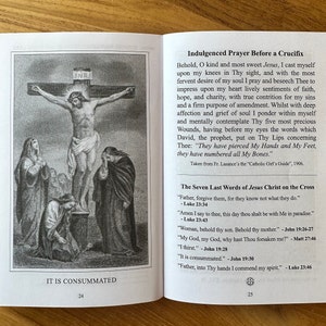May include: An open book displaying pages 24 and 25. Page 24 features a black and white illustration of the crucifixion with the text IT IS CONSUMMATED. Page 25 contains the Indulged Prayer Before a Crucifix and The Seven Last Words of Jesus Christ.