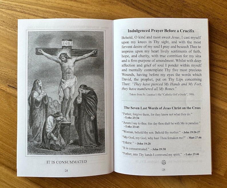 May include: An open book displaying pages 24 and 25. Page 24 features a black and white illustration of the crucifixion with the text IT IS CONSUMMATED. Page 25 contains the Indulged Prayer Before a Crucifix and The Seven Last Words of Jesus Christ.