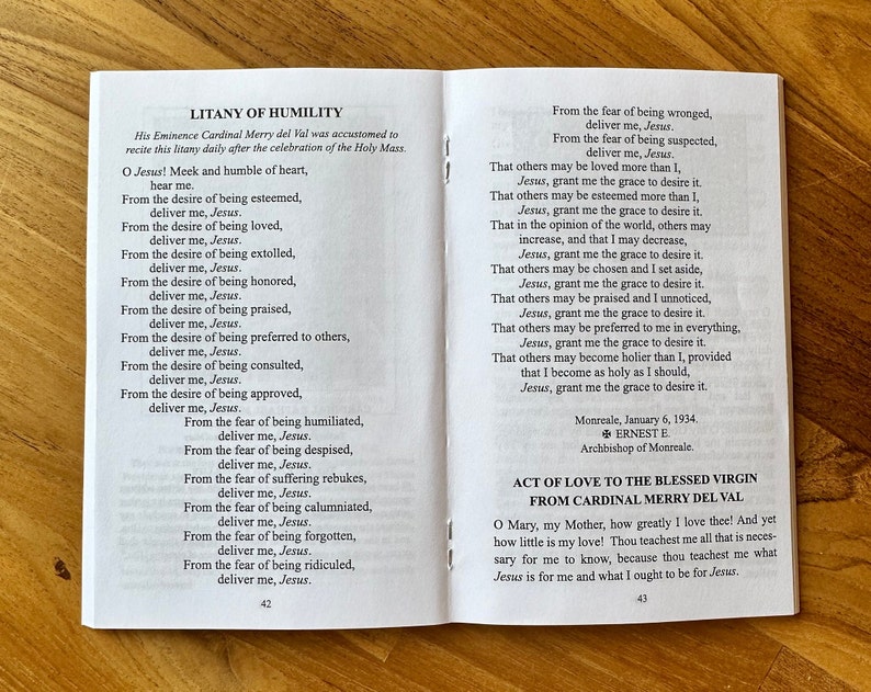 May include: An open booklet displaying the Litany of Humility and an Act of Love to the Blessed Virgin. The white pages feature black printed text, including prayers and religious titles, with page numbers 42 and 43 visible at the bottom.