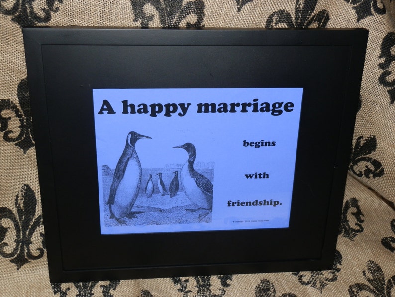 May include: A framed print with a blue background featuring a quote about marriage and penguins. The quote reads "A happy marriage begins with friendship."