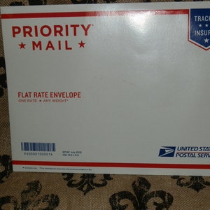 May include: White Priority Mail flat rate envelope with red and blue text and a blue star. The envelope has a red and blue "TRACKED INSURED" label with three stars. The text on the envelope reads "PRIORITY MAIL", "FLAT RATE ENVELOPE", "ONE RATE ANY WEIGHT", "PS00001000014", "EP4F July 2015", "00:12.595", "UNITED STATES POSTAL SERVICE".