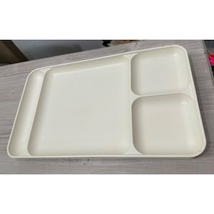 May include: A cream-colored divided tray with four compartments. The tray has a long, rectangular section, two square sections, and a long, narrow section. The tray is made of a smooth, solid material.