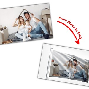 May include: A family of three, a man, a woman, and a child, are sitting on the floor in front of a pile of cardboard boxes. They are holding up a cardboard box over their heads to form a house shape. The image is printed on a white flag.
