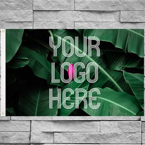 May include: A rectangular horizontal banner featuring a vibrant green tropical leaf background with a small pink flower bud in the center. The white text YOUR LOGO HERE is printed in a bold, triple-lined sans-serif font across the foliage.
