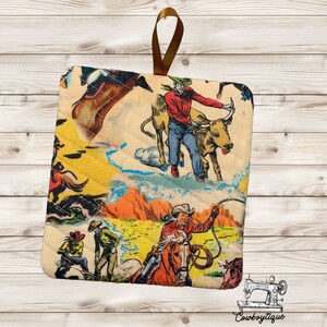 May include: A set of two quilted pot holders featuring a vintage illustration of cowboys riding horses and bulls. The pot holders are yellow, red, blue, and brown with a white quilted background.