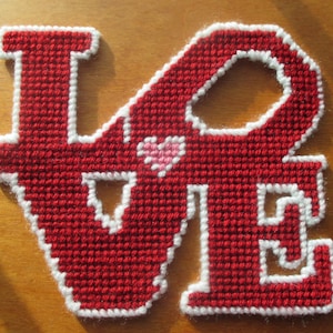 May include: Red felt letters spelling "LOVE" with white outlines. A small pink heart is in the center of the letters.