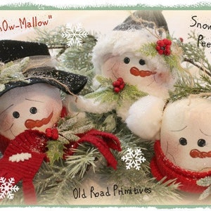 May include: Three snowman ornaments with red scarves and white hats. The snowman on the left has a black hat and the text "Snow-Mallow" above it. The snowman on the right has a red scarf and the text "Snowmen Peeps" above it. The text "Old Road Primitives" is at the bottom of the image.