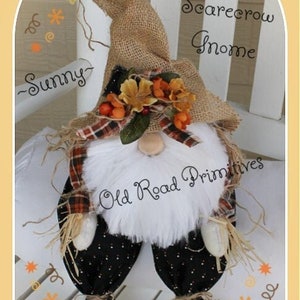 May include: A scarecrow gnome with a burlap hat, plaid scarf, and black and white polka dot trousers. The gnome is sitting on a white bench with the text "the Scarecrow Gnome" and "Old Road Primitives" written on the bench.