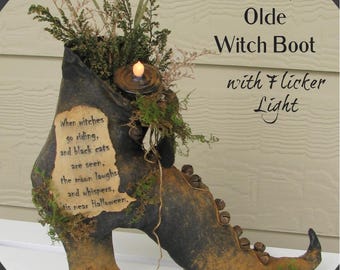 May include: A dark, distressed witch boot decoration featuring a flickering LED light, green foliage, and small metal bells. A parchment-style label reads: When witches go riding, and black cats are seen, the moon laughs and whispers, 'tis near Halloween.