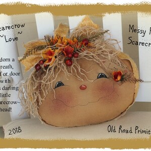 May include: A handmade scarecrow head with messy hair, a painted face, and a burlap body. The scarecrow is wearing a wreath of fall leaves and berries. The text "Scarecrow ~Love~" and "Messy Hair Scarecrow" is written on the image.