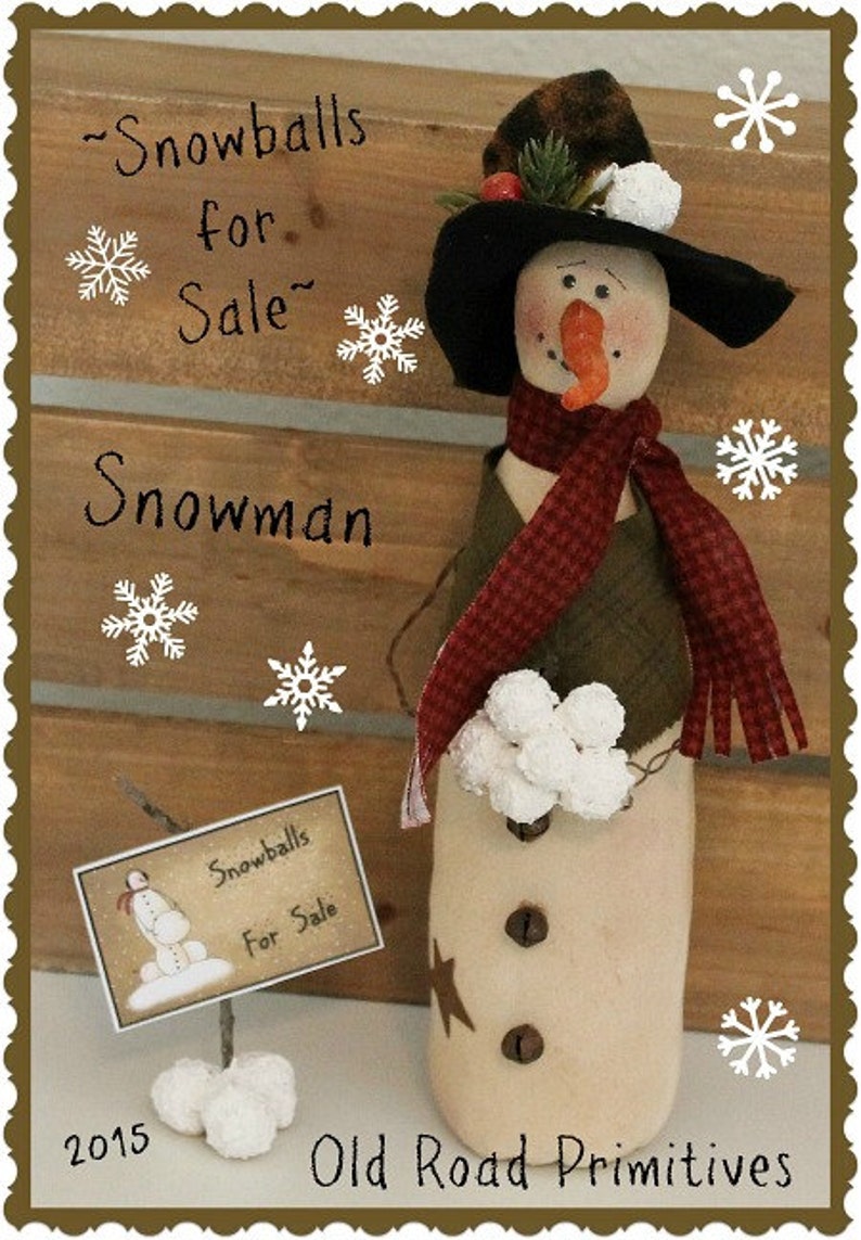 May include: A handmade snowman doll with a black hat, red and white scarf, and a sign that says "Snowballs for Sale". The snowman is holding a bunch of white snowballs. The background is a wooden wall with a rustic look.
