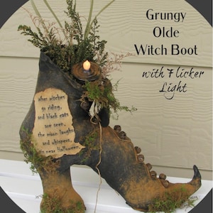 May include: A dark, distressed witch boot decoration featuring a flickering LED light, green foliage, and small metal bells. A parchment-style label reads: When witches go riding, and black cats are seen, the moon laughs and whispers, 'tis near Halloween.
