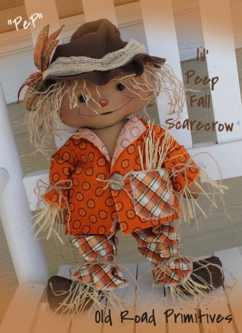 Puede incluir: Una mu&ntilde;eca de espantap&aacute;jaros de oto&ntilde;o hecha a mano con un sombrero de fieltro marr&oacute;n, pantalones de cuadros naranja y blanco y un sombrero de fieltro marr&oacute;n. La mu&ntilde;eca est&aacute; sentada en un banco de madera blanco. El texto "Lil' Peep Fall Scarecrow" est&aacute; escrito en el banco.