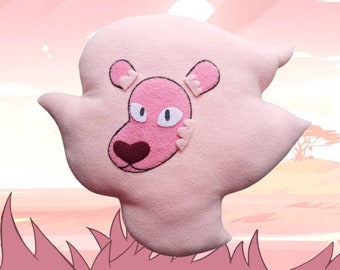 May include: Pink plush lion head pillow with embroidered details. The lion has pink ears with heart-shaped details, pink eyes, and a brown nose.