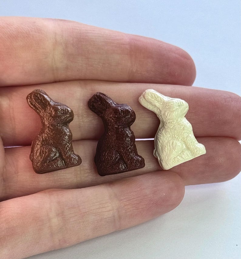 May include: Three chocolate bunny figurines, one brown, one dark brown, and one white.
