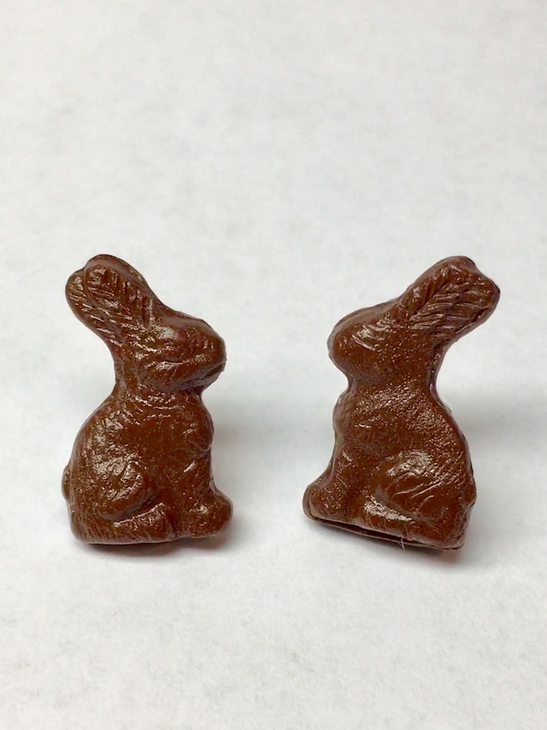 May include: Two brown chocolate bunny figurines. The bunnies are sitting upright with their ears perked up.
