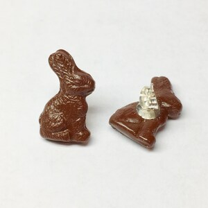 May include: A pair of brown chocolate bunny stud earrings. The earrings are made of a smooth, brown material and have a silver post.
