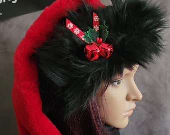 May include: A red and black faux fur Santa hat with a holly and bell embellishment. The hat has a long, flowing red fur tail.  originalsbyeva.etsy.com