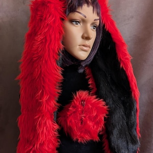 May include: A red and black faux fur hood with long, bunny-like ears. The hood is displayed on a mannequin. The text "originalsbyeva.etsy.com" is visible in the background.