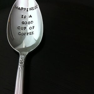 May include: A silver teaspoon with the inscription "Happiness is a good cup of coffee" engraved on the bowl.