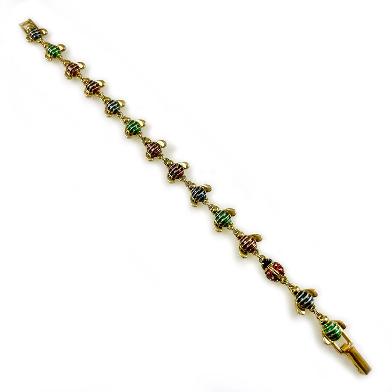 May include: A gold bracelet with a chain and colorful turtle charms. The turtles are striped with green, red, and blue enamel.