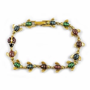 May include: A gold bracelet with a chain of small, colorful enamel ladybugs. The ladybugs are in shades of green, red, and blue.