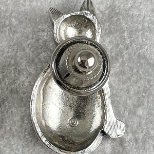 May include: Silver cat-shaped cabinet knob with a round, silver base. The knob is designed to be used on a cabinet door or drawer.