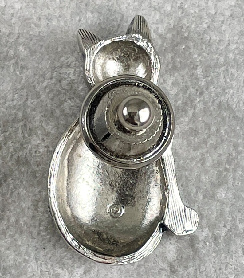 May include: Silver cat-shaped cabinet knob with a round, silver base. The knob is designed to be used on a cabinet door or drawer.