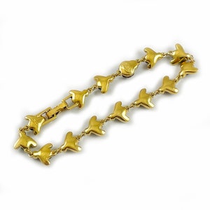 May include: A gold-tone bracelet with a chain link design. Each link is shaped like a bird with a small, clear stone in the center. The bracelet has a clasp closure.