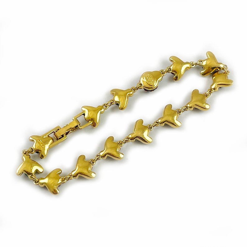 May include: A gold-tone bracelet with a chain link design. Each link is shaped like a bird with a small, clear stone in the center. The bracelet has a clasp closure.
