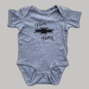K&ouml;nnte beinhalten: Ein grauer Baby-Strampler mit einem schwarzen Chevrolet-Logo und dem Text "Pure Baby" auf der Vorderseite.
