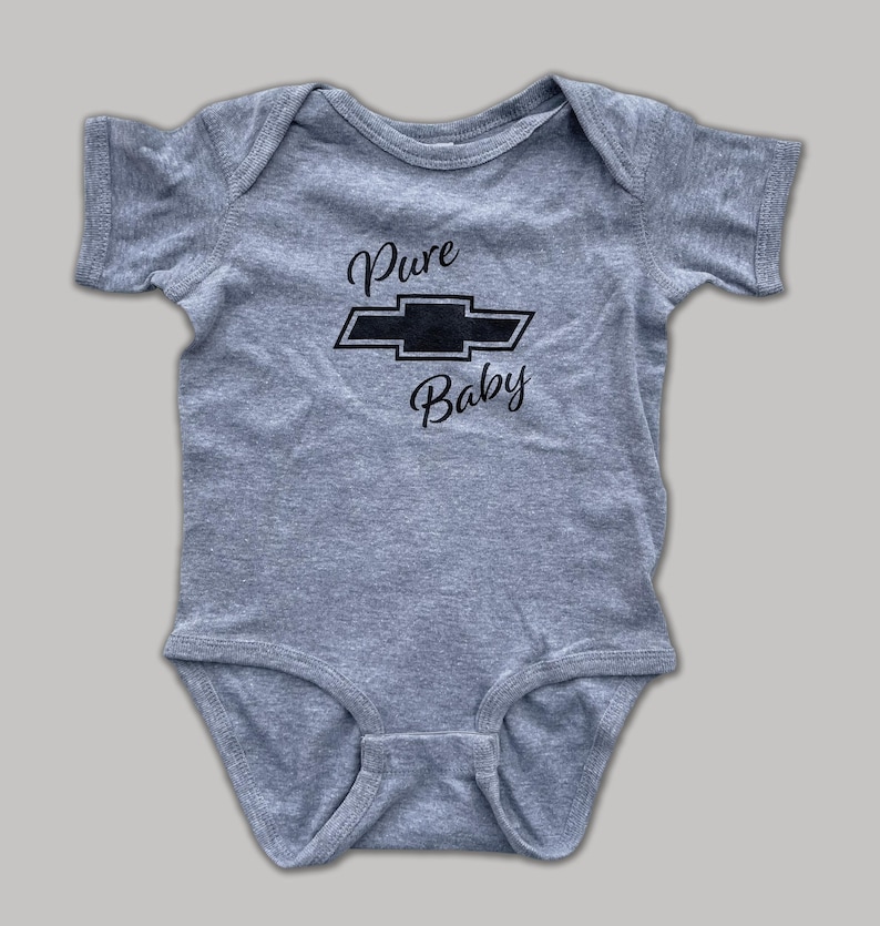 K&ouml;nnte beinhalten: Ein grauer Baby-Strampler mit einem schwarzen Chevrolet-Logo und dem Text "Pure Baby" auf der Vorderseite.