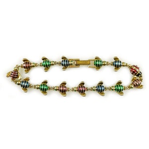 May include: A gold bracelet with a series of bee-shaped charms. The bees are striped in red, green, and blue enamel.