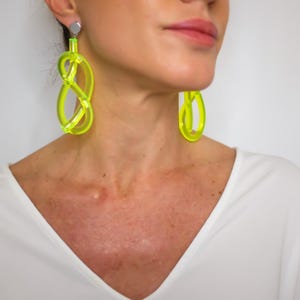 Puede incluir: Pendientes llamativos de color amarillo neón. Estos audaces pendientes presentan un diseño abstracto único. Son un accesorio brillante y llamativo, perfecto para añadir un toque de color a cualquier atuendo. Los pendientes están hechos de un material translúcido.
